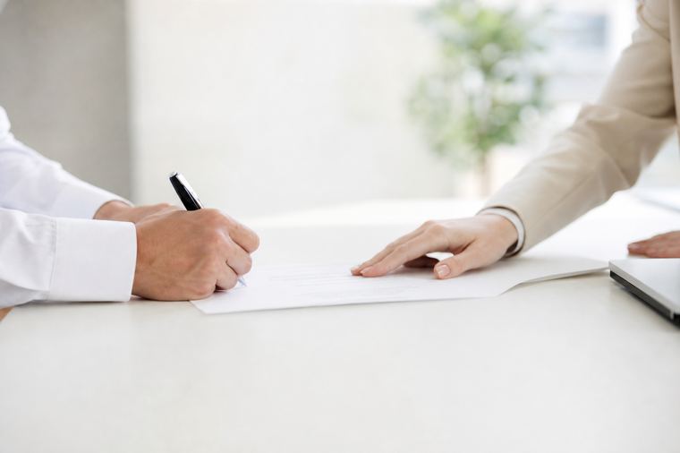 Le mani di una persona reggono un foglio stampato in bianco e nero davanti a sé.